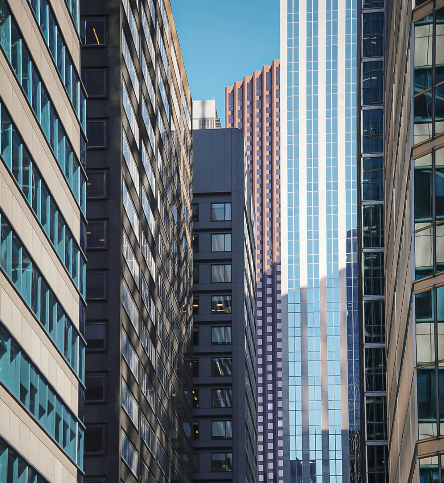 Office towers packed along a city street, seen from below